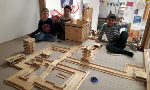 Drei Buben sind in einem Spielzimmer und bauen Gebilde aus Holz