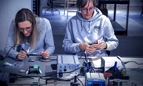 Hier sieht man Frauen bei der Arbeit mit Lötkolben und anderen elektronischen Geräten