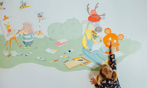 Ein Kleinkind greift auf die Tierillustrationen an der Wand