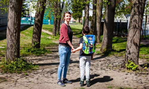 Eine Frau hält ein Schulkind an der Hand