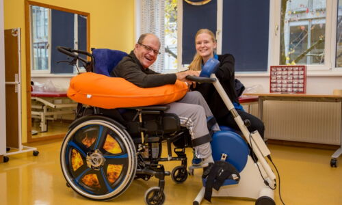 Ein Mann im Rollstuhl sitzt an einer Therapierad