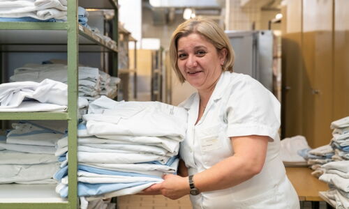 Eine Frau sortiert Arbeitsmäntel und Bettwäsche ein.